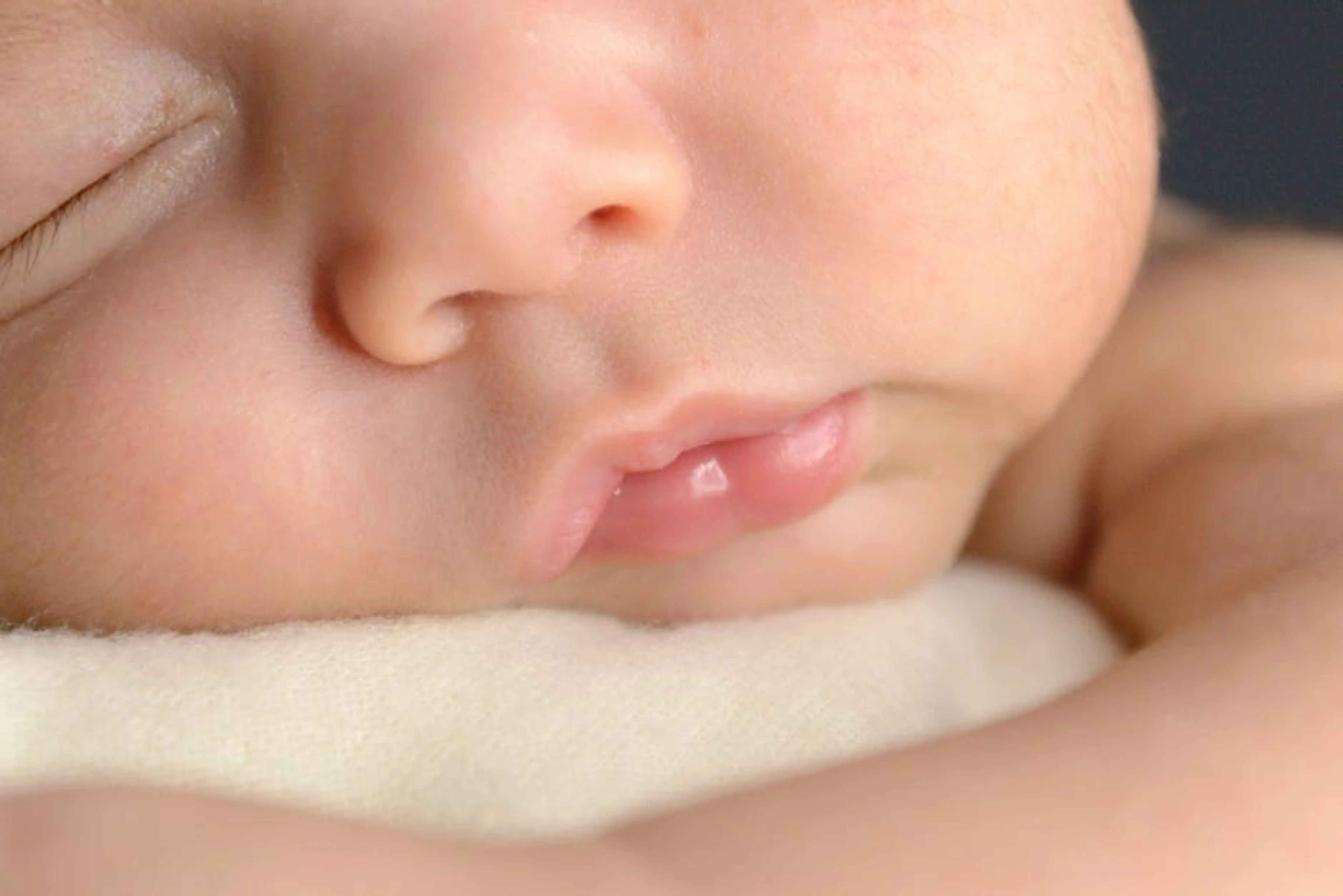 A serene close-up of a newborn baby peacefully sleeping, capturing soft details. A newborn baby sleeping peacefully in a bassinet, illustrating early infant sleep patterns.