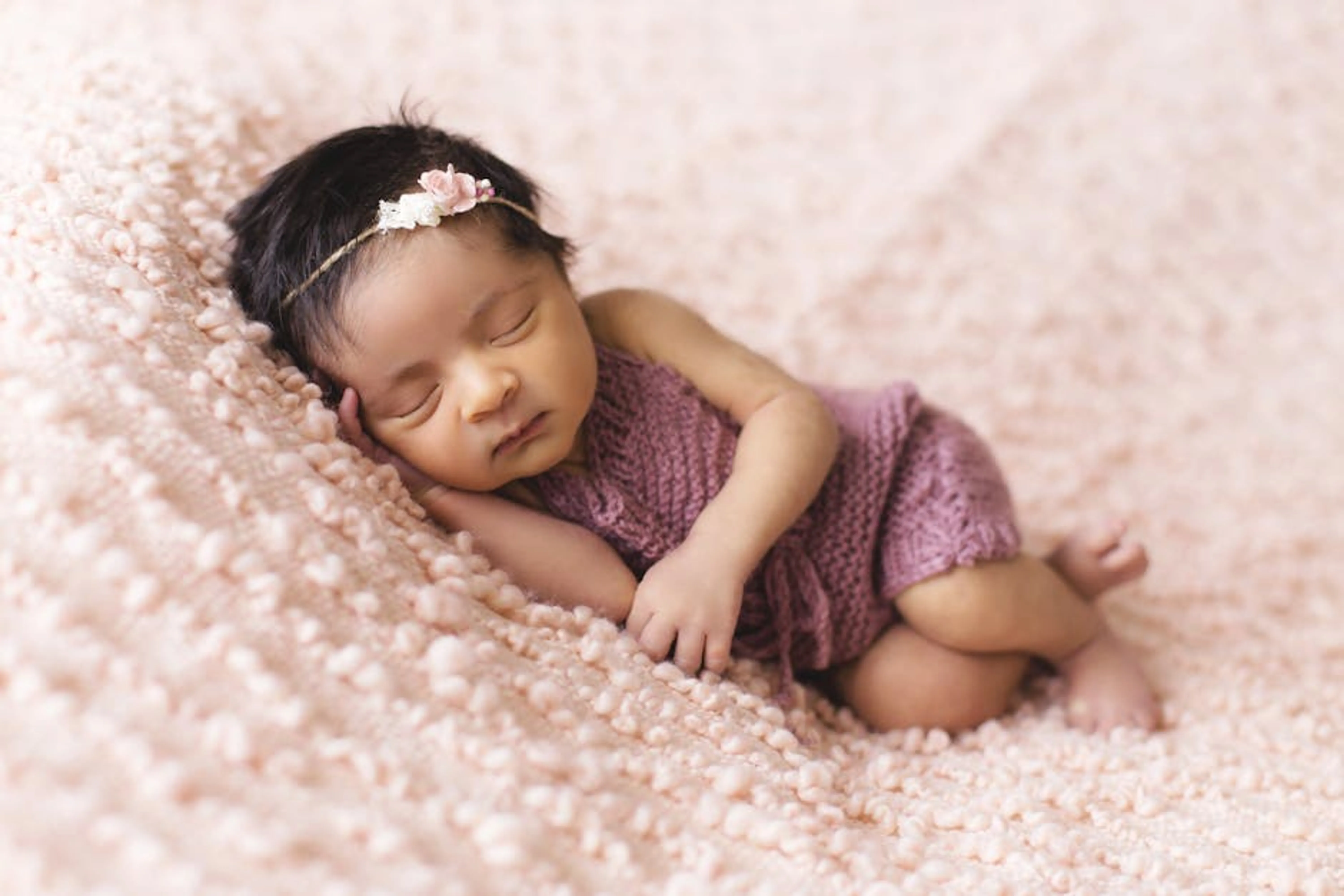A newborn baby girl peacefully sleeps on a soft pink blanket, embodying innocence and tranquility. A parent gently rocking a baby to sleep, illustrating comfort and solutions.