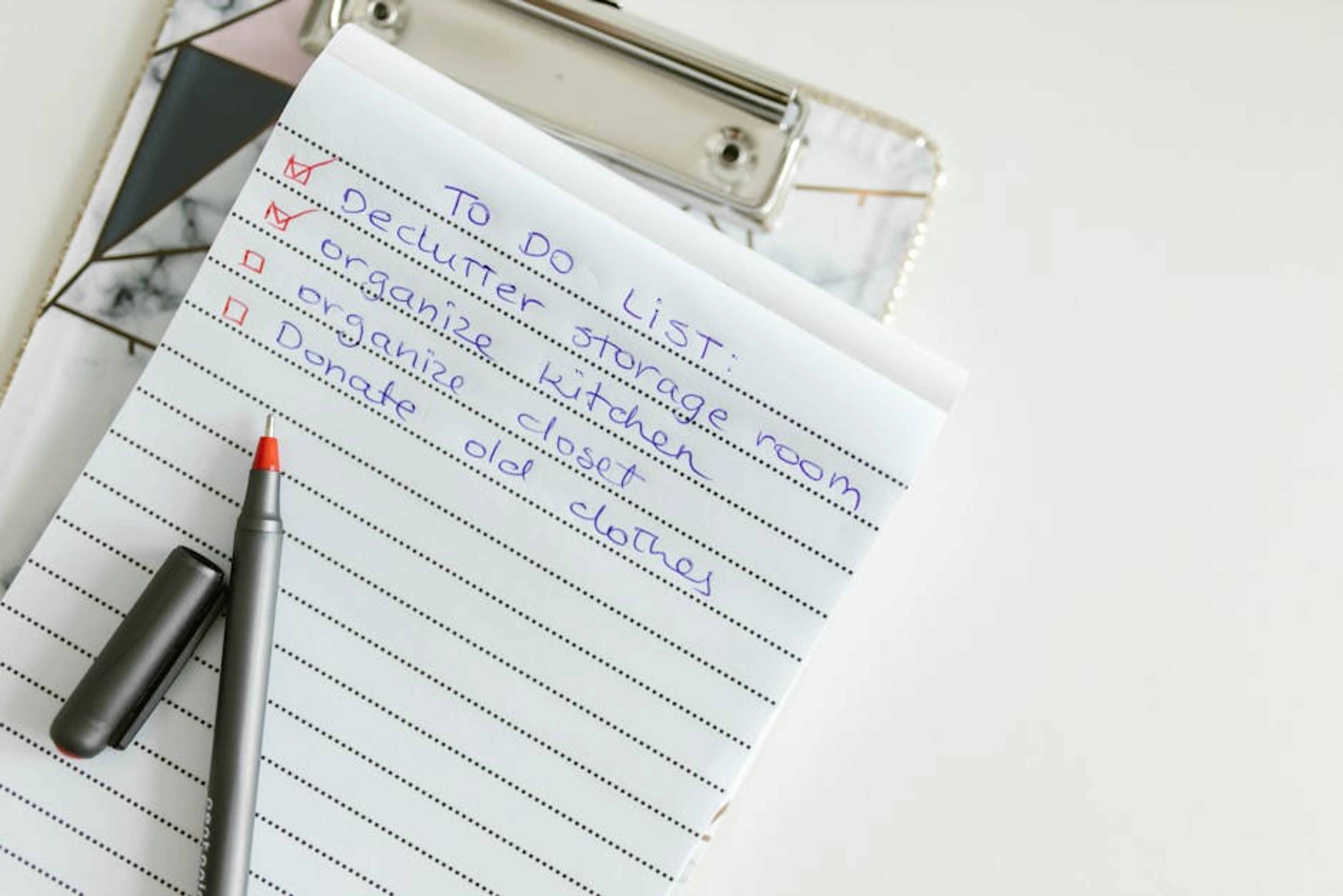 A neatly written to-do list on lined paper with a pen, perfect for organizing tasks. Boxes labeled keep, donate, trash, and relocate, ready for a decluttering session
