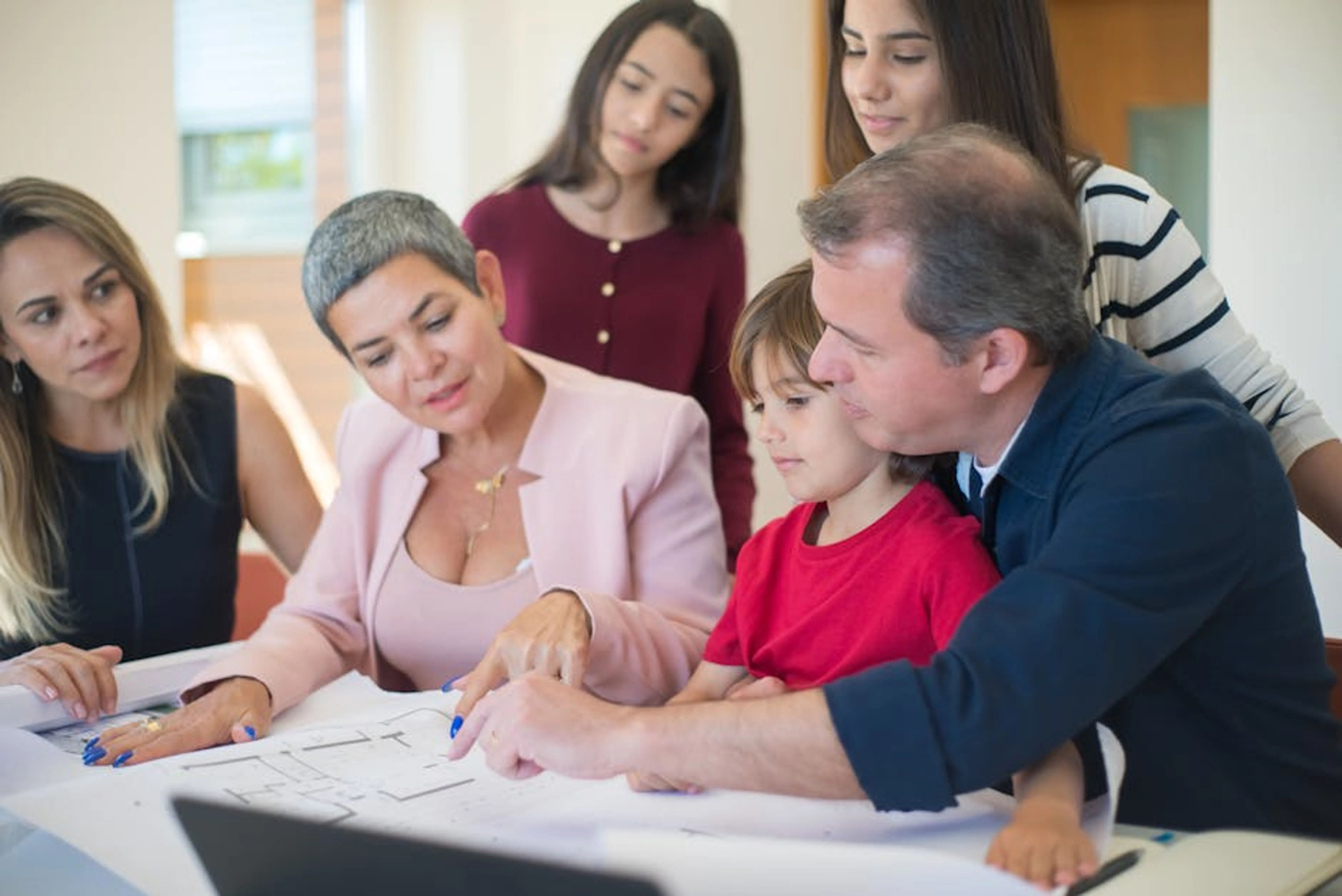 Family meeting with realtor to discuss house plans, emphasizing real estate decision-making. A family sitting around a table reviewing documents, symbolizing the importance of family and estate planning.