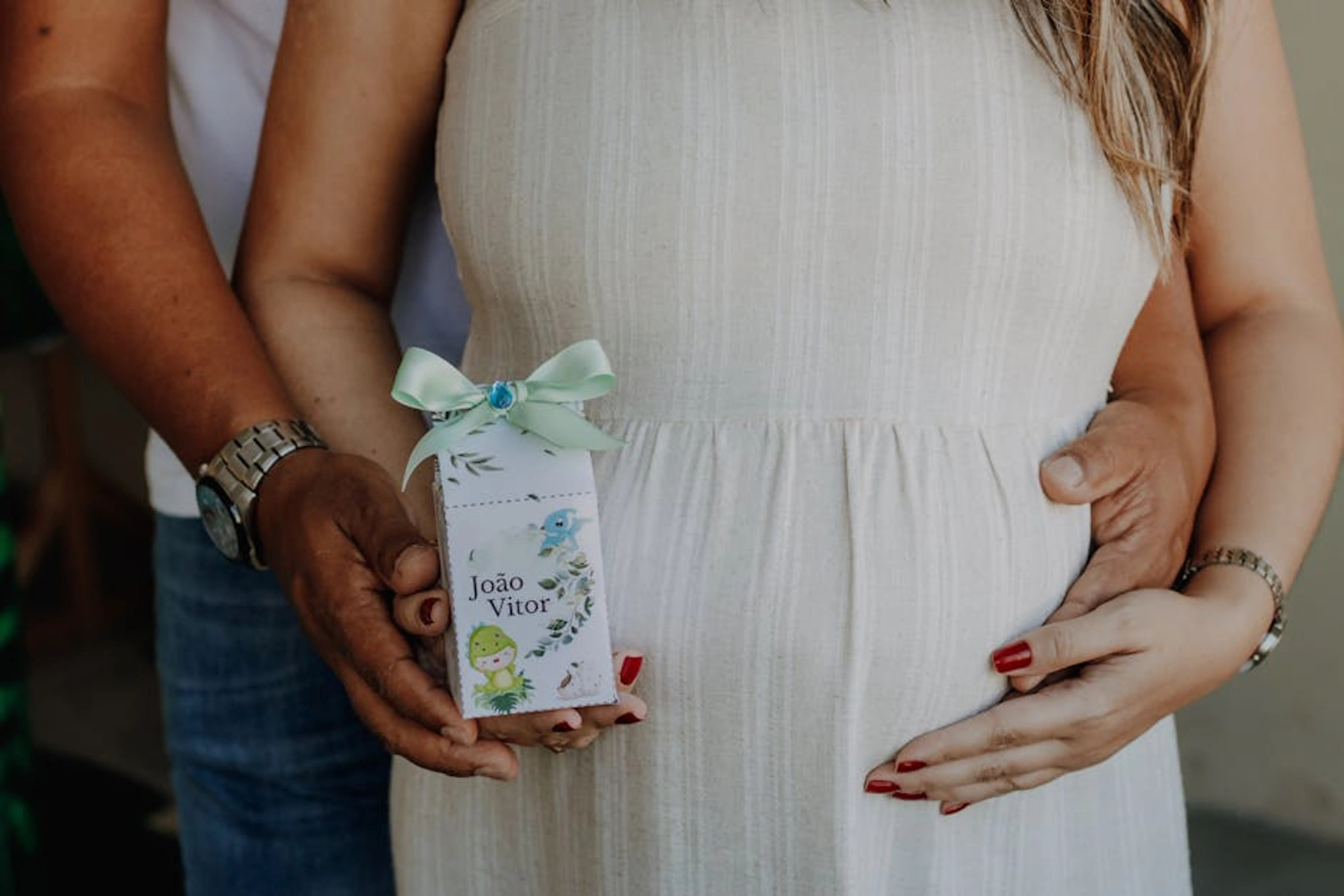 Pregnant couple sharing a tender moment, holding a personalized baby shower gift. A person thoughtfully looking at documents, representing future planning and making important decisions.