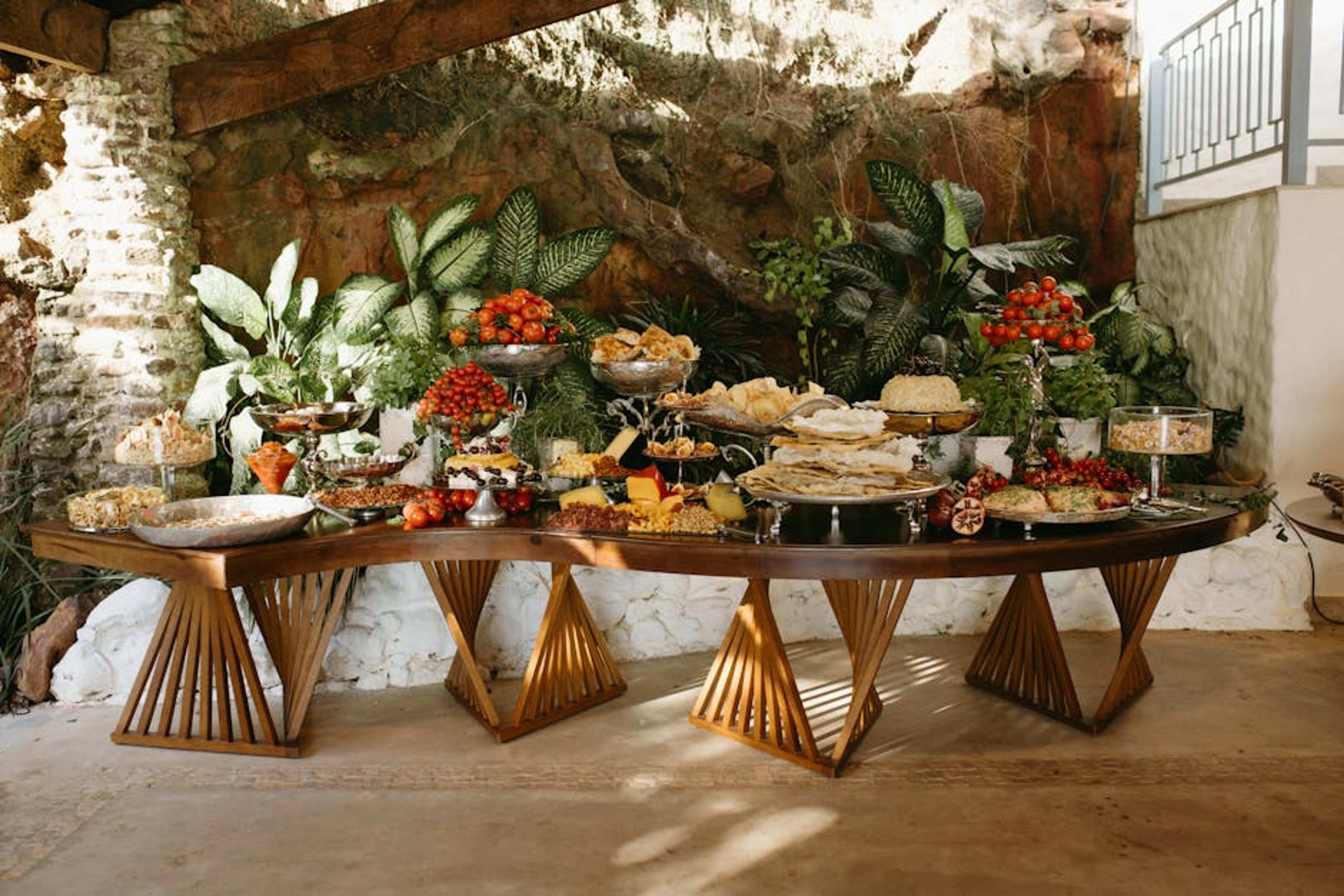 A lavish buffet table with assorted foods and vibrant greenery background. A piggy bank with coins and a retirement savings chart in the background, symbolizing long-term financial planning.