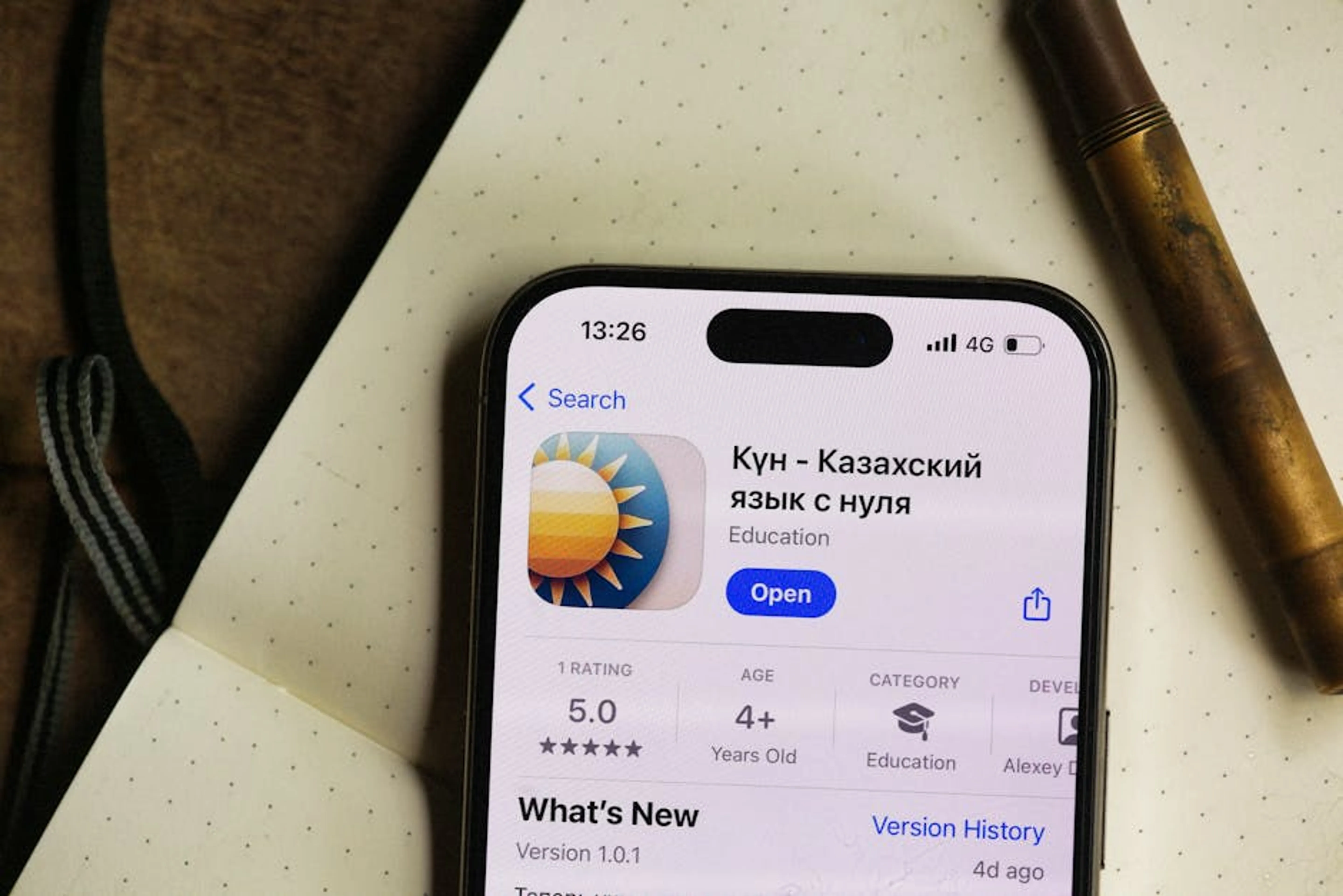 Smartphone displaying a Kazakh language learning app in a cozy setting. Person using a language learning app on a smartphone, illustrating technology's role