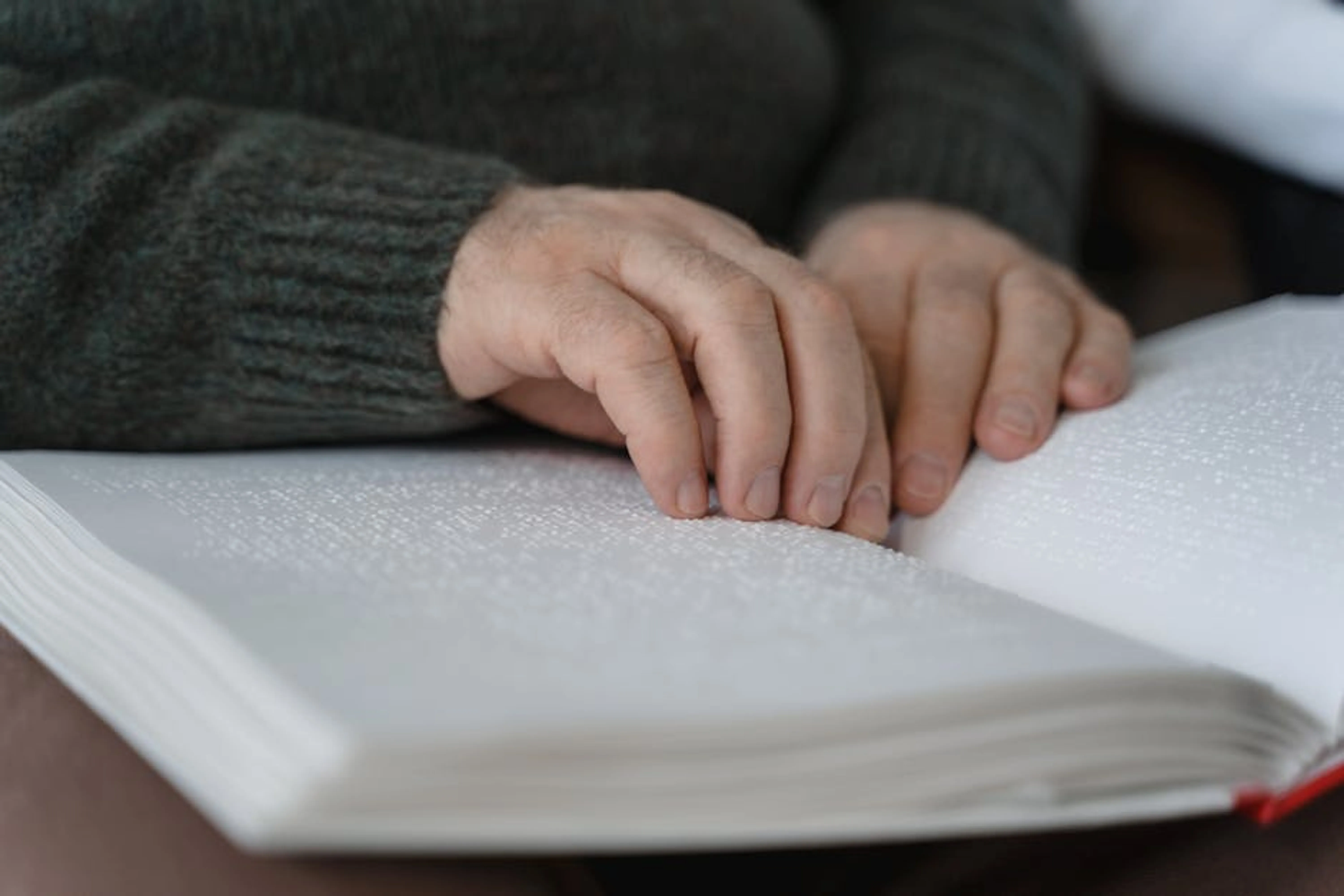 Close-up of hands reading a braille book, emphasizing accessibility and tactile learning. A person adapting to new learning technology on a tablet