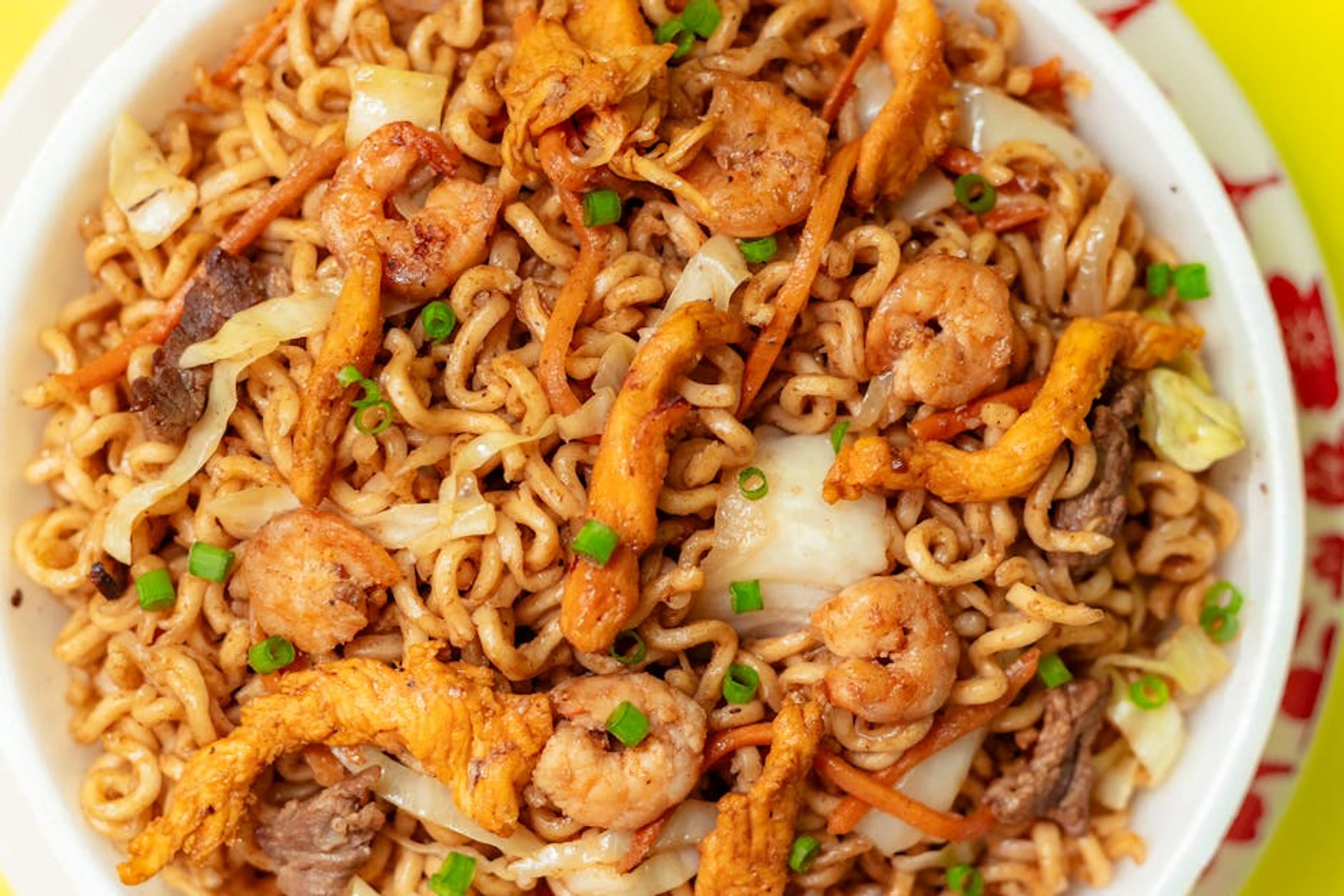 Close-up of a flavorful yakisoba stir-fry with shrimp, chicken, and vegetables in a bowl. A vibrant chicken and vegetable stir-fry served in a bowl with chopsticks