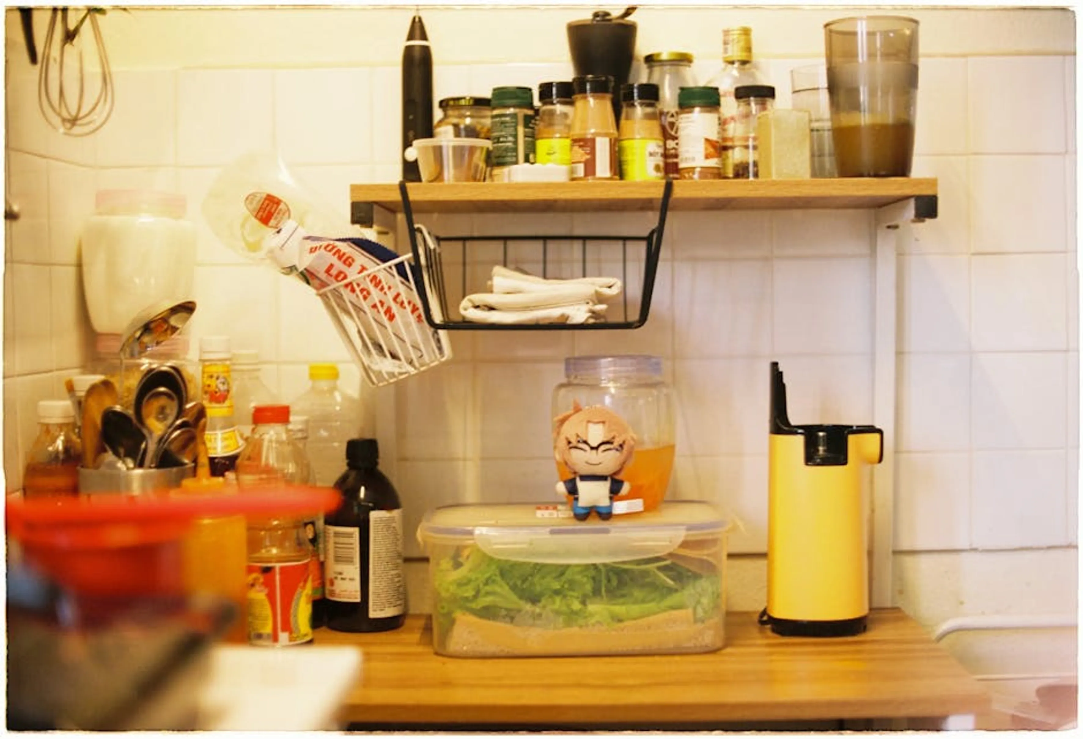 A small kitchen counter with spice rack, containers, and utensils for efficient storage. Various essential kitchen tools neatly arranged on a counter, ready for cooking