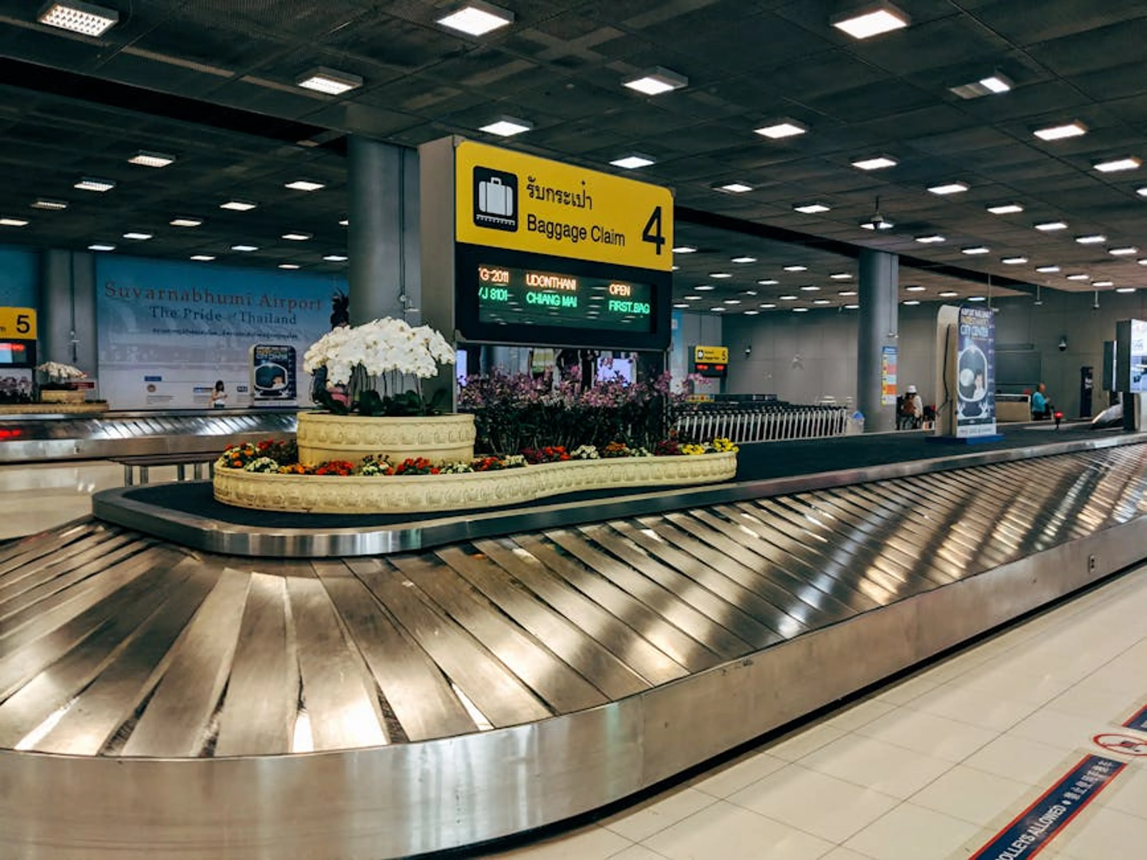 Modern baggage claim area at Suvarnabhumi Airport in Bangkok with luggage carousel and signage. A traveler looking concerned at an empty luggage carousel at an airport