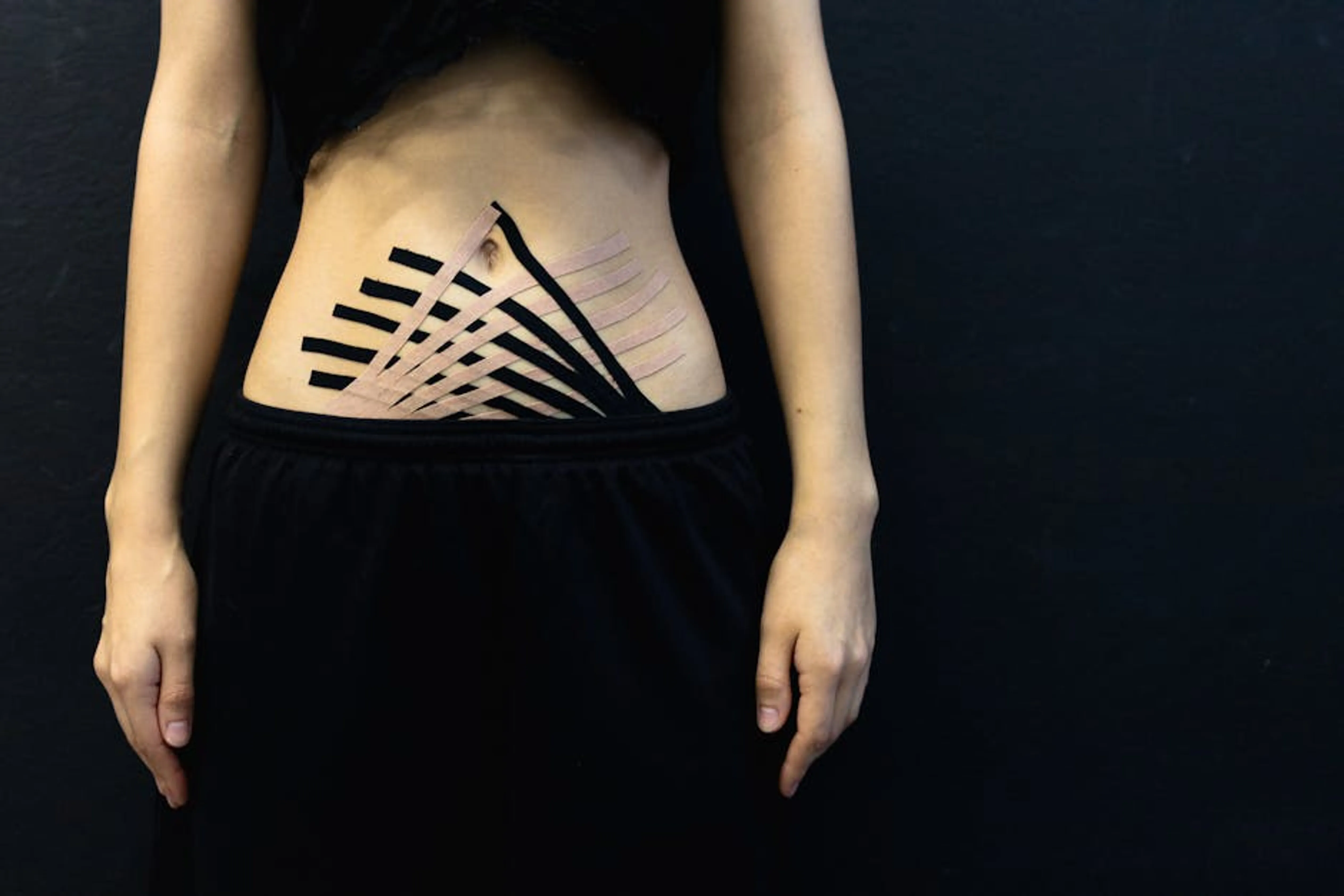 Female abdomen with kinesiology tape for physical therapy on black background. Diagram showing the deep core muscles including transverse abdominis, pelvic floor, diaphragm, and multifidus